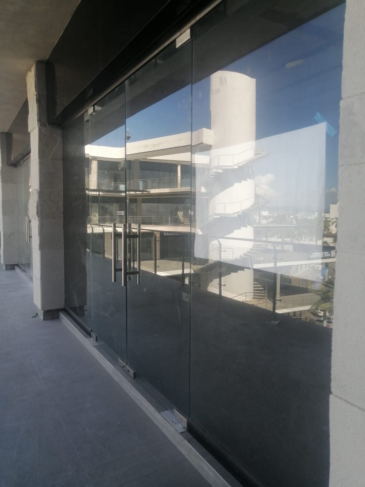 Acceso exterior formado por puertas y paños de cristal oscuro