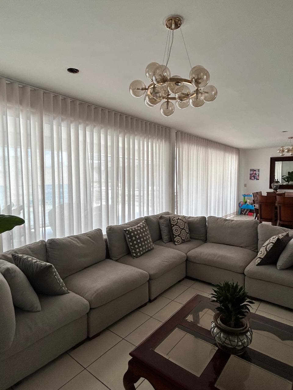 Sala con cortinas claras de onda perfecta frente a ventanales